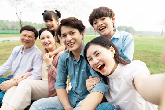 image of an asian family sitting together on the grass at the park