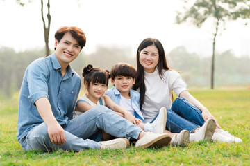 image of an asian family sitting together on the grass at the park