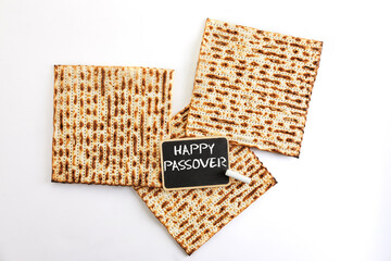 Pesach celebration concept - Jewish holiday Pesach. Three square matzahs lie together, isolated on white background. Black board with the inscription Happy Passover
