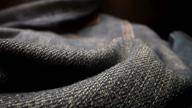 macro shot of jeans pants thrown on floor, closeup view of fabric, moving shot, trendy modern cloth