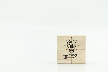 hand holding open lock in light bulb icons on wooden cubes. symbolizing copyright or patent...