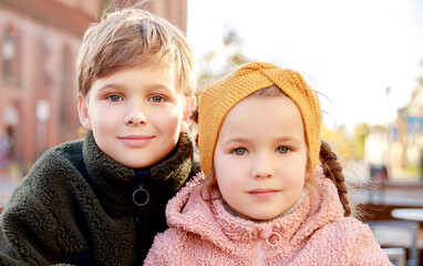 Close-up portrait of a girl and a boy. The children sit next to each other. Happy childhood, beautiful faces. Children outdoors. Children's portrait.
