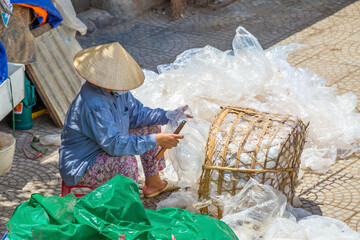 A person sitting sorting through a basket full of plastic bags at Hanoi in Vietnam