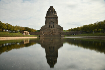 Pond reflecting the Monument to the Battle of the Nations in Leipzig, Germany against a cloudy sky