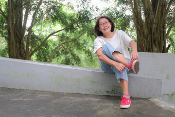 Asian woman sitting alone in the park, fixing her shoe lace, after a long walk