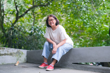 Asian woman sitting alone and taking a rest after a long walk in the park