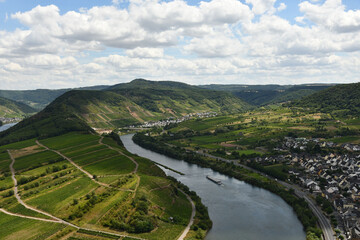 Fototapeta na wymiar Bird's eye view of a village near the Moselle loop surrounded by greenery and vineyards in Germany