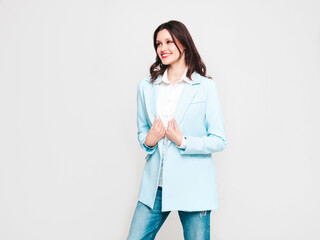 Portrait of young beautiful brunette woman wearing nice trendy blue suit jacket and jeans. Sexy fashion model posing in studio. Fashionable female isolated on white. Cheerful and happy