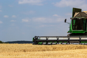 Fototapeta premium Photo of combine harvester that is harvesting wheat with dust straw in the air