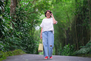 Asian woman in casual clothes walking in quiet green beautiful park