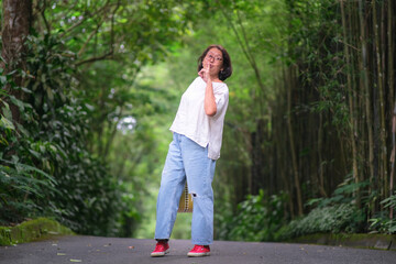 Asian woman in casual clothes walking in quiet green garden