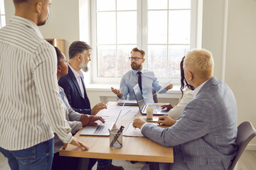 Group of business people chatting on a meeting. Company employees talking in the office and making great decisions with brainstorming. Cowokers listen to their colleague at the working place.