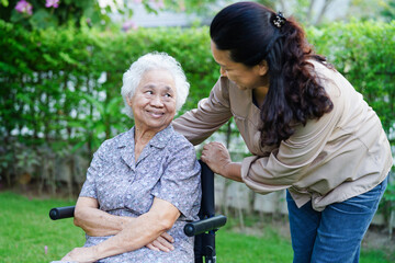 Caregiver help Asian elderly woman disability patient sitting on wheelchair in park, medical...