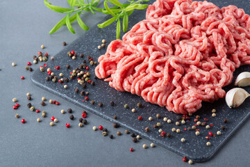 Fresh raw minced beef on backing paper and cutting board and ingredients