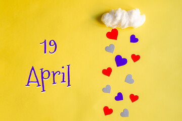 19 april day of month, colorful hearts rain from a white cotton cloud on a yellow background. Valentine's day, love and wedding concept