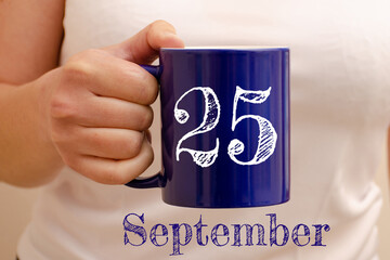 The inscription on the blue cup 25 september. Cup in female hand, business concept