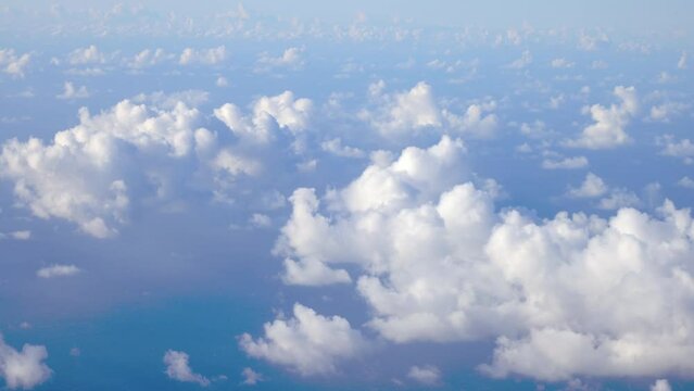 Flying over fluffy white clouds in hazy atmosphere