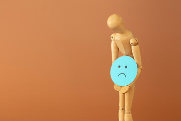 Wood model with sadness and depression concept, on brown background.
