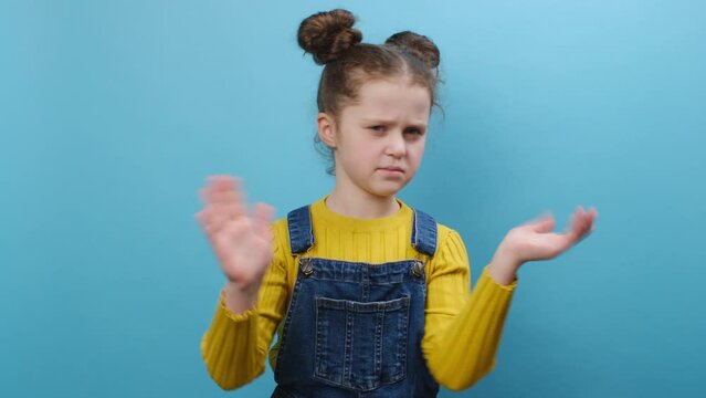 Portrait of sad little girl kid wearing casual clothes smelling something stinky and disgusting, intolerable smell, holding breath with fingers on nose, isolated on blue background. Bad smell concept