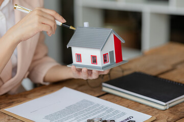 Young businesswoman or real estate agent signing contract for home insurance, real estate investment advisor, property insurance. Real estate agent offers a house.