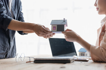 A real estate agent is handing over a small house plan with house keys to the buyer after the purchase contract has been signed. real estate trading ideas