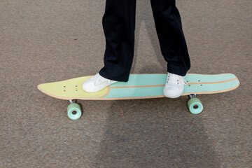Fototapeta na wymiar Young girl boy foot in sneakers skateboarder on long board skate in street