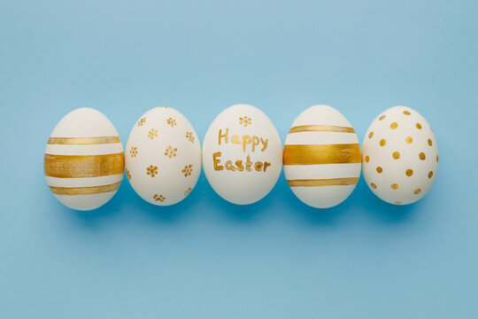 Easter background. Easter golden decorated eggs on blue background. Minimal easter concept. Flat Lay of Golden Easter Eggs