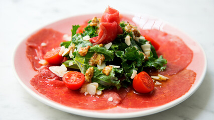 Kale salad with beef carpaccio and cheese.