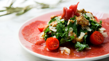 Kale salad with beef carpaccio and cheese.
