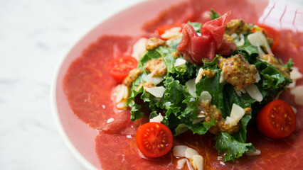 Kale salad with beef carpaccio and cheese.
