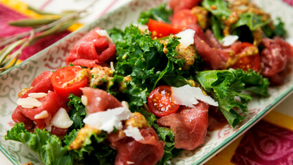 Kale salad with beef carpaccio and cheese.