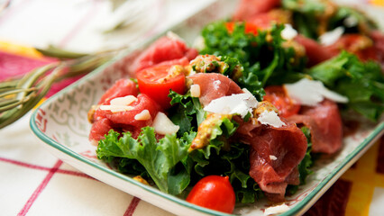 Kale salad with beef carpaccio and cheese.