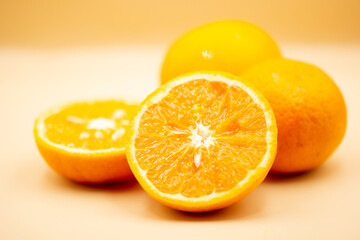 Oranges on pink background. One orange is cut in half, the other is whole.