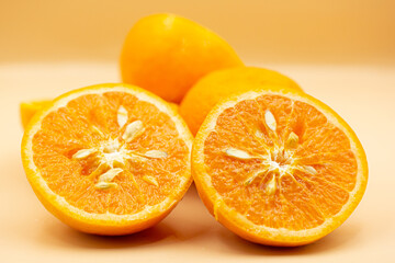Oranges on pink background. One orange is cut in half, the other is whole.