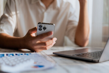 Close up of young man using calculator and laptop for doing financial mathematics on wooden table in office and working background - business, tax, accounting, statistics and analytical research conce