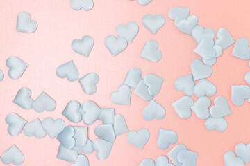 Texture made of blue textile confetti in a heart shape on a pink glittering background.