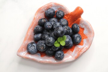 Fresh blueberries with mint leaves. The fruits are actual berries with many tiny seeds and are deep indigo to black color when ripe. Copy space.