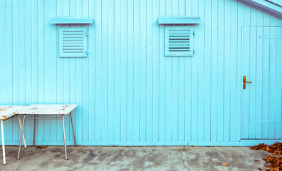 Fototapeta na wymiar Blue wooden shed with small windows and two tables in front