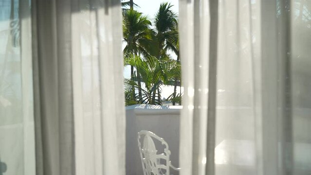 Looking through the hotel curtains to the palm tree and beach view out the balcony