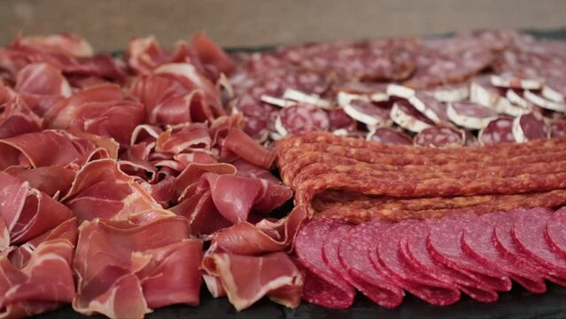 Meat plate with assortment of various tasty Spanish, french or Italian appetizers - sliced prosciutto, sausage, salami, kabanos sausages, fuet. Meat platter rotating