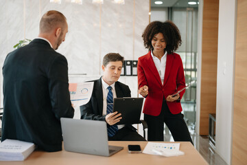 Office colleagues have a casual discussion. During a meeting in a conference room, a group of business teem sit in the conference room new startup project..