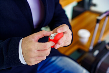 Close up photo of a man holding his air pods in his hands, they are in red case