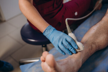 closeup hand of woman doctor doing an ultrasound of the legs of a man and knee