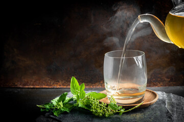 Herbal tea in a cup with basil leaves on rustic wooden table. Basil is food and herb for healthy.