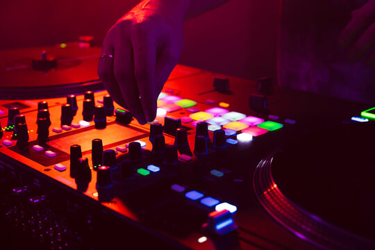Close up of DJ hands on dj console mixer during concert in the club