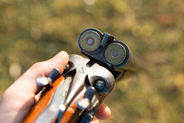 Midsection of man unloading shotgun while standing on field