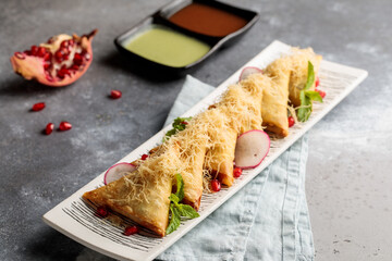 Samboosas or samosas with chutney, raita and chilli sauce served in dish isolated on table top view of arabic breakfast