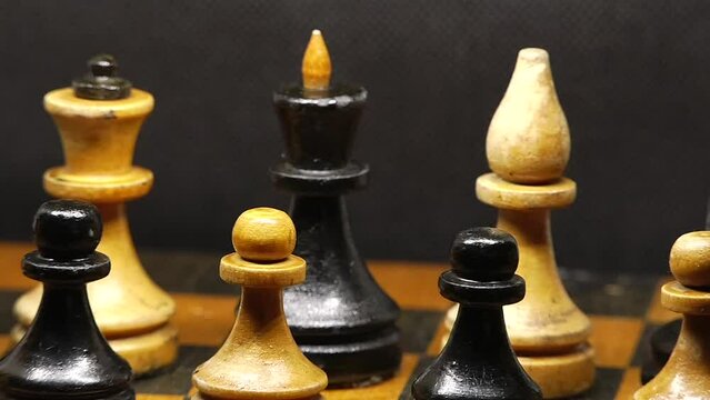 Black and white wooden chess pieces on a chessboard in a very close up video	
