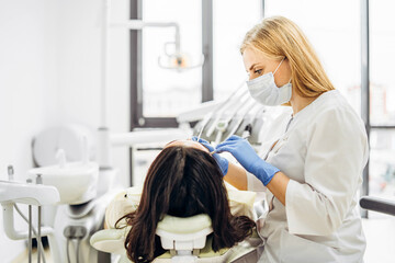 Female dentist with female patient in dental chair providing oral cavity treatment.