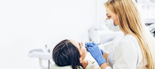 Female dentist with female patient in dental chair providing oral cavity treatment.